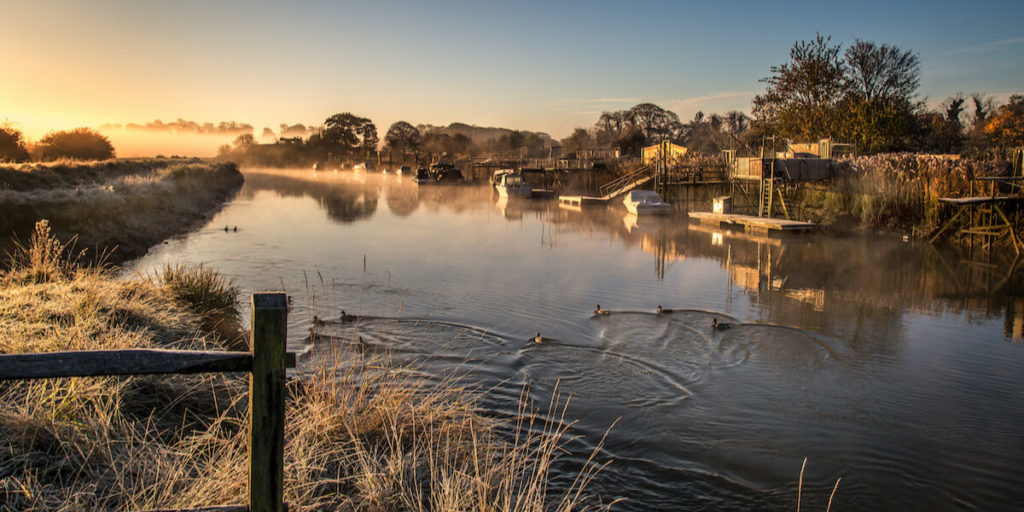 sunrise over river arun and ducklings swimming down the river