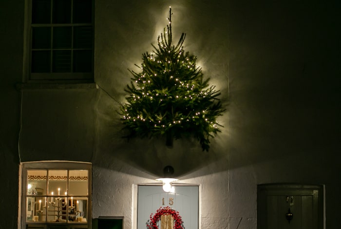 lit christmas tree attached to house